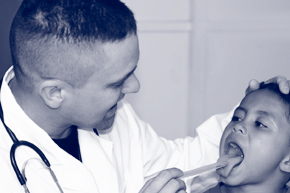 Medical worker uses a tongue depressor to check a young patient's throat